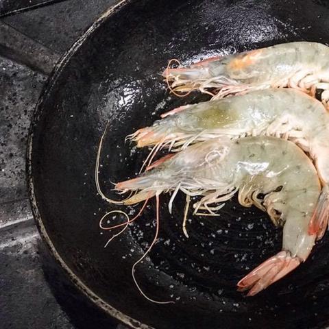 Whole shrimp cooking in a cast-iron skillet