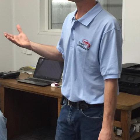 A Simply Shrimp team member in a company polo shirt, talking about the farm