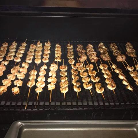 Rows of shrimp skewers on a grill
