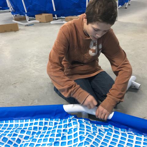 A young helper working beside one of the blue pool tanks