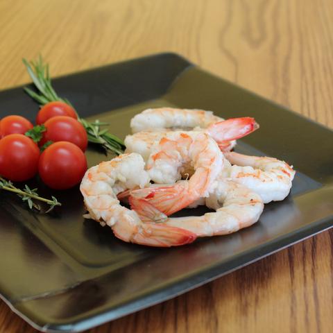 Cooked shrimp on a black plate with cherry tomatoes