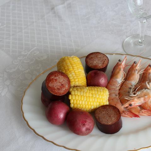 A shrimp boil plate with corn, potatoes and sausage
