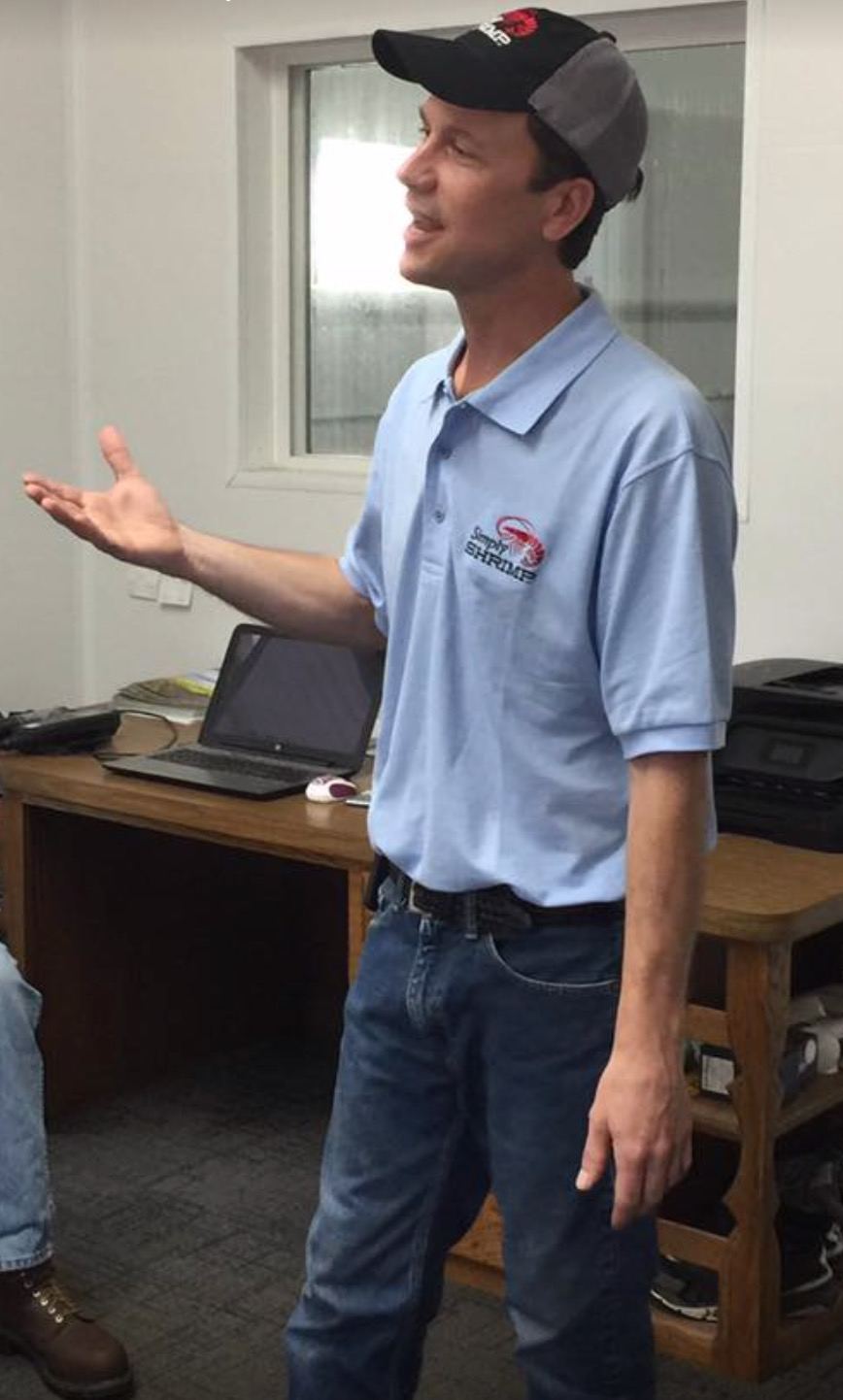 A Simply Shrimp team member in a company polo shirt, talking about the farm